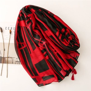 Detailed view of red and black contrast patterned scarf with red tassel fringe ornaments