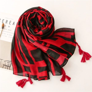 Detailed view of red and black geometric scarf with fringe tassels and thin fabric texture