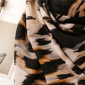 Primer plano de bufanda con estampado de leopardo, textura suave y detalles de borlas