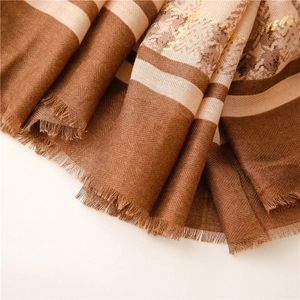 Close-up of herringbone cotton scarf with gold floral patterns and fringe details