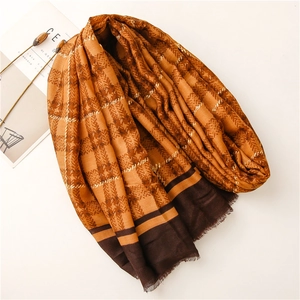 Detailed view of orange and brown plaid scarf with herringbone pattern and fringe edges