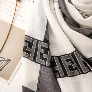 Detailed macro view of woven scarf fabric featuring geometric letter patterns and textures
