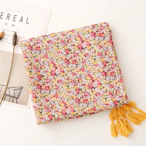Detail of floral scarf with yellow tassels beside Cereal magazine on light background