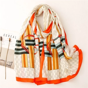 Close-up of long silk scarf featuring orange chain patterns and letter print design