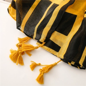 Detailed close-up of yellow and black geometric scarf featuring stylish fringe tassels