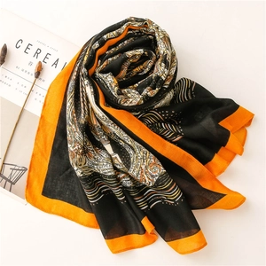 Fashionable black and orange printed scarf with wave patterns on a minimalist tabletop