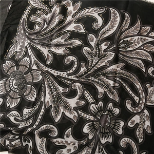 Nahaufnahme von Vintage-Blumenmuster mit Goldblatt-Details auf leichtem Stoffschal
