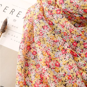 Detailed macro shot of floral cotton-linen scarf with small yellow blossoms and fringes
