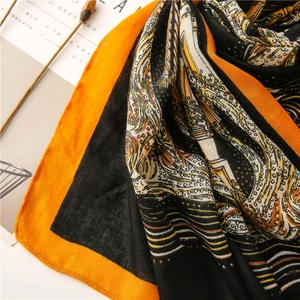 Detail of artistic gold and black fluid pattern on silk-feel scarf with marigold border