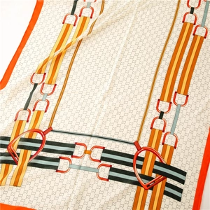 Detailed close-up of silk scarf with luxury horsebit patterns and orange borders