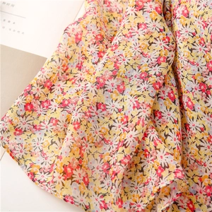 Close-up of lightweight yellow floral cotton scarf showing soft texture and tassel detail