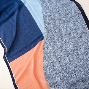Detail of color-block scarf with geometric patterns and fringe textures on a white background
