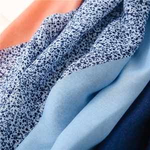 Detailed macro view of vibrant floral print scarf with light blue and orange hues