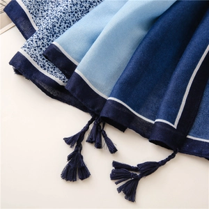 Detail of blue gradient cotton linen scarf featuring floral prints and handmade tassels