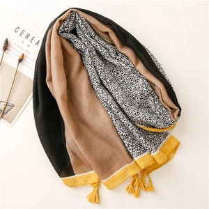 Detail of color-block cotton linen shawl featuring black floral patterns and yellow tassels