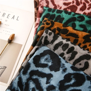 Detail of leopard print scarves in five colors stacked next to a lifestyle magazine