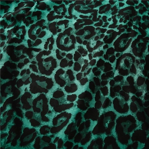 Macro shot of emerald green leopard print fabric showing soft velvet texture and drape