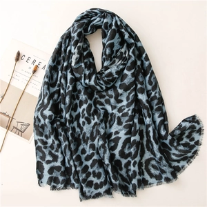 Blue and black leopard print scarf with fringe details laid on a minimalist background