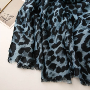 Close-up of blue and black leopard print scarf with soft fringe edges and herringbone texture