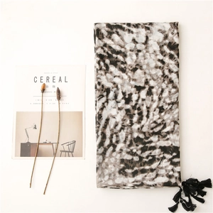 Detail of soft cotton-linen scarf with ink pattern print and black tassel accents