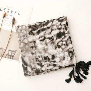 Detail of soft winter scarf with black tassels and abstract ink pattern on white background