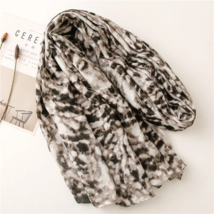 Flat lay of lightweight leopard print scarf with artistic neutral tones and soft texture