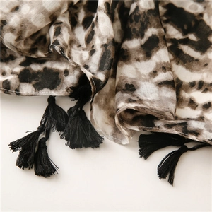 Close-up of leopard print scarf featuring delicate black handmade tassels and soft fabric