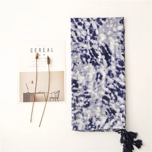 Blue tie-dye scarf detail with tassels next to dried flowers and a lifestyle magazine