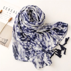 Detailed view of light marble print scarf featuring blue tassels and soft airy texture