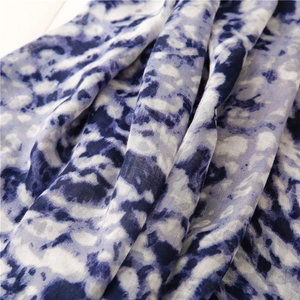 Detail of soft yellow and blue tie-dye linen scarf featuring delicate braided tassel edges