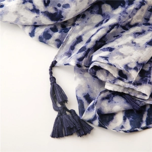 Detail of blue and white tie-dye scarf featuring handcrafted tassels and soft fabric texture