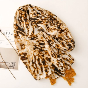 Soft leopard print shawl with yellow tassels and minimalist lifestyle backdrop