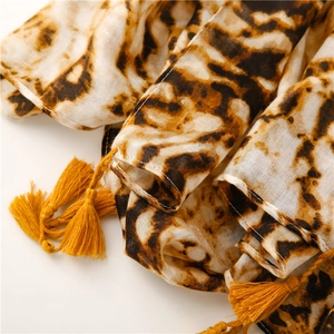 Close-up of leopard print cotton scarf featuring golden yellow tassel corner details