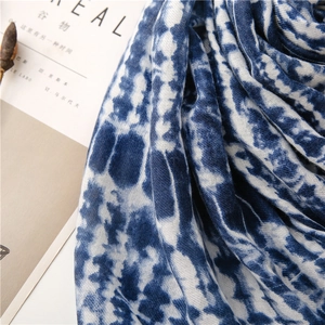 Detailed close-up of blue tie-dye scarf fabric with textured weave and soft draping effect