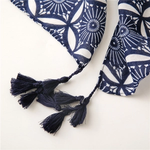 Macro shot of ethnic kaleidoscope pattern and blue handmade tassels on cotton linen scarf
