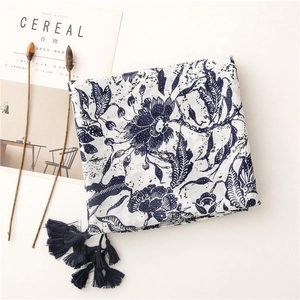 Detail of vintage blue floral scarf with elegant tassels and leaf patterns on white fabric