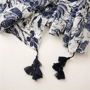 Detailed close-up of blue floral bohemian scarf featuring artisanal tassels and linen texture