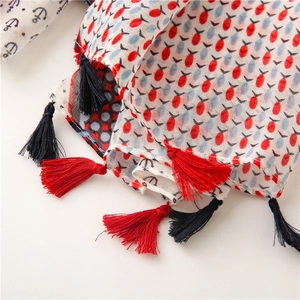 Close-up of anchor print scarf fabric with detailed red and black handmade tassels