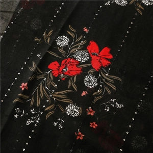 Détail de tissu imprimé floral avec fleurs rouges blanches et lignes de paillettes argentées