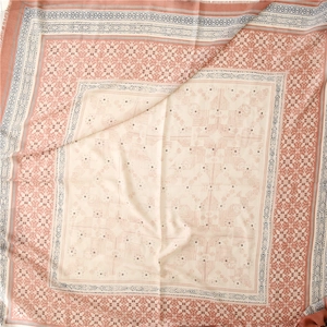 Detail of soft geometric patterned scarf with delicate frayed edges in pink and cream