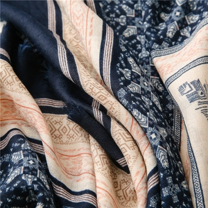 Detail of ethnic geometric patterns and soft fringed edges on navy and pink linen-feel scarf