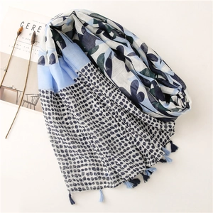 Blue linen scarf with cherry leaf print and tassels on a minimalist white desk