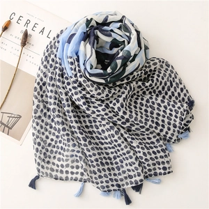 Close-up of blue and green leaf print scarf with cotton tassels and soft fabric texture