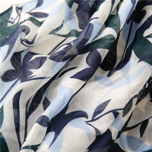 Detail of blue cherry leaf print on linen-feel fabric with fine woven texture and tassels