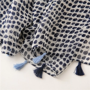 Detail of blue leaf pattern scarf with dual-tone tassels on white cotton linen fabric