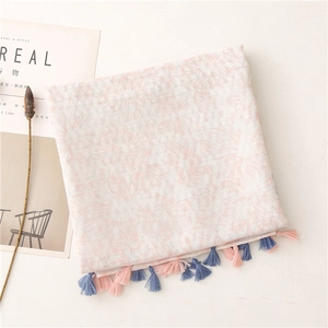 Detailed view of pink and white scarf featuring floral prints and handmade tassels