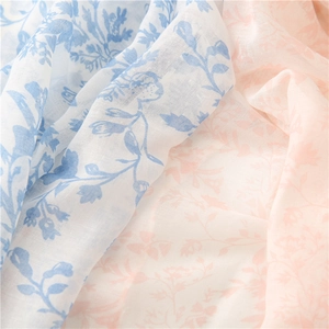 Close-up of lightweight floral scarf showing blue and pink botanical patterns and fine texture