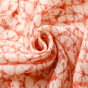 Nahaufnahme von weichem orangefarbenem Batikstoff mit feiner Textur und Libellenprint