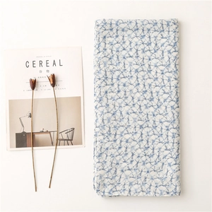 Blau-weißer Schal mit Batik-Gittermuster neben Trockenblumen und einer Zeitschrift