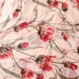 Detailopname van een linnen-look sjaal met rode en roze distelbloemenprint